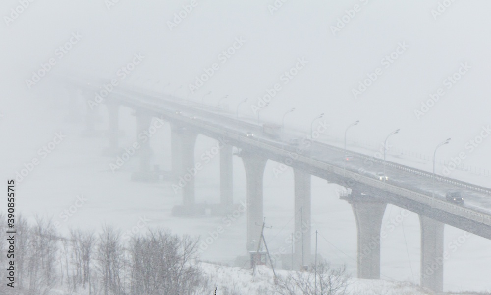The bridge over the frozen Kama river with cars in snowstorm in winter, Russia. Poor visibility. The bridge over the frozen Kama river with cars in snowstorm in winter, Russia. Poor visibility.