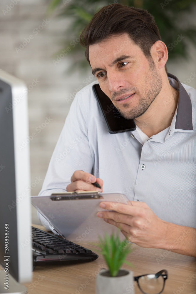 man filling form while talking to customer on the phone man filling form while talking to customer on the phone
