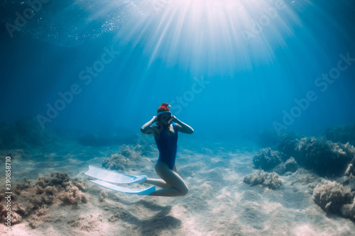 Christmas holidays party with freediver. Happy freediver woman with New year cap glides underwater with fins in ocean.