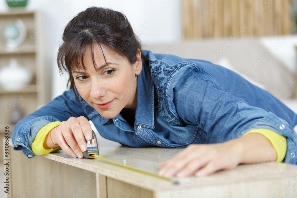 woman measuring a piece of wood woman measuring a piece of wood