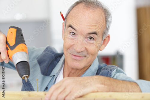 senior worker using drill at construction site photo