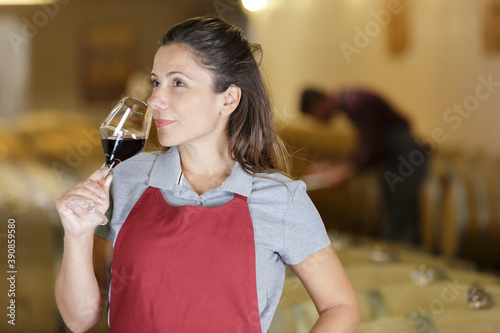 smiling woman drinking red wine at a cellar