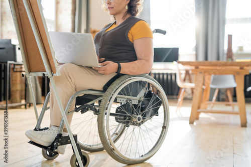Young businesswoman in wheelchair using laptop while preparing presentation