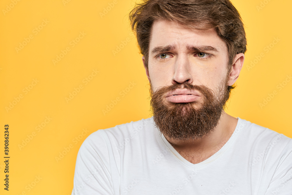 Man in white t-shirt emotions studio gestures with hands displeased facial expression yellow background Man in white t-shirt emotions studio gestures with hands displeased facial expression yellow background