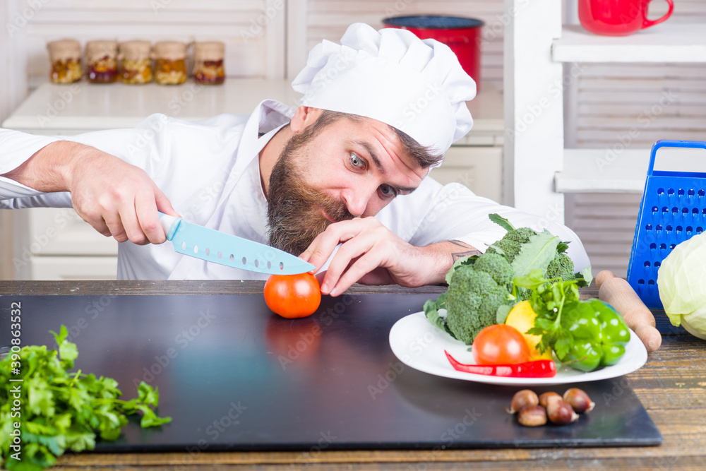 Cook cut tomato. Cooking. Cutting and chopping. Handsome bearded chef in uniform. Ingredients. Professional kitchen. Cook cut tomato. Cooking. Cutting and chopping. Handsome bearded chef in uniform. Ingredients. Professional kitchen.