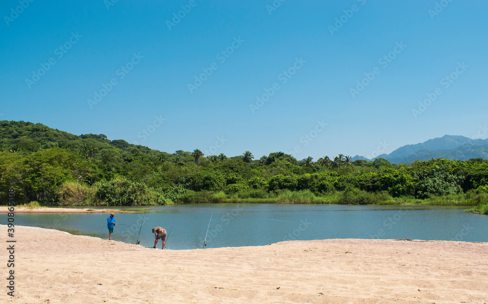 A group of people fishing in a mexican beach of the pacific coast  with a beautiful landscape in the background, and a clear and blue sky of a sunny day