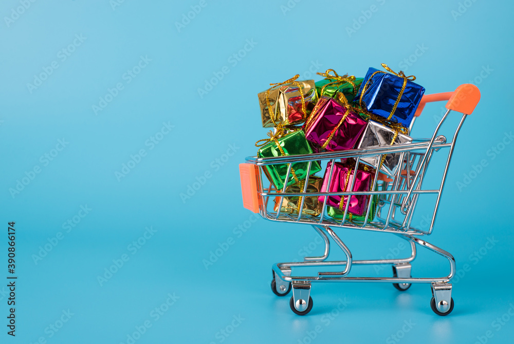 Spend finance on bargains purchase concept. Close up side profile full size photo of miniature basket carry filled with heap of colorful packages isolated bright blue background Spend finance on bargains purchase concept. Close up side profile full size photo of miniature basket carry filled with heap of colorful packages isolated bright blue background