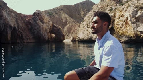 A man sitting on a boat looking to the beauty of big rocks on the sea in El jebha city, Morocco. enjoy the