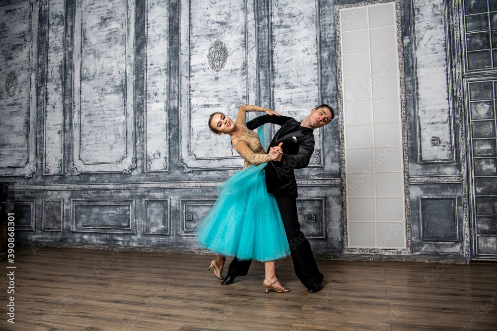 young couple in evening dance costumes dancing tango in the ballroom