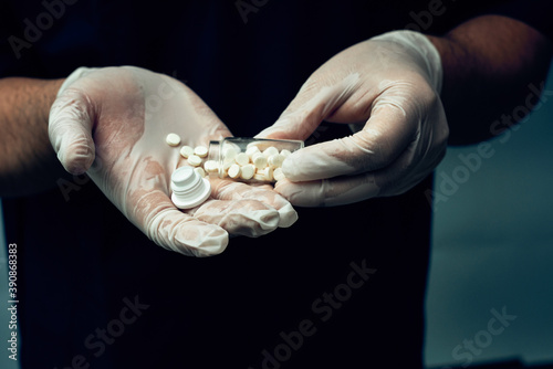 A jar of pills in the hands of a doctor, hands in gloves.