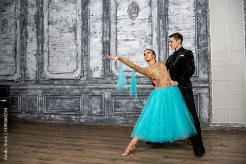 young couple in evening dance costumes dancing tango in the ballroom