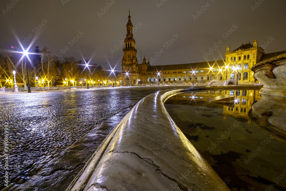 Obraz premium Plaza de España en Sevilla, Andalucía, foto nocturna con lluvia y reflejos en suelo y fuente lateral, foto con gran angular.