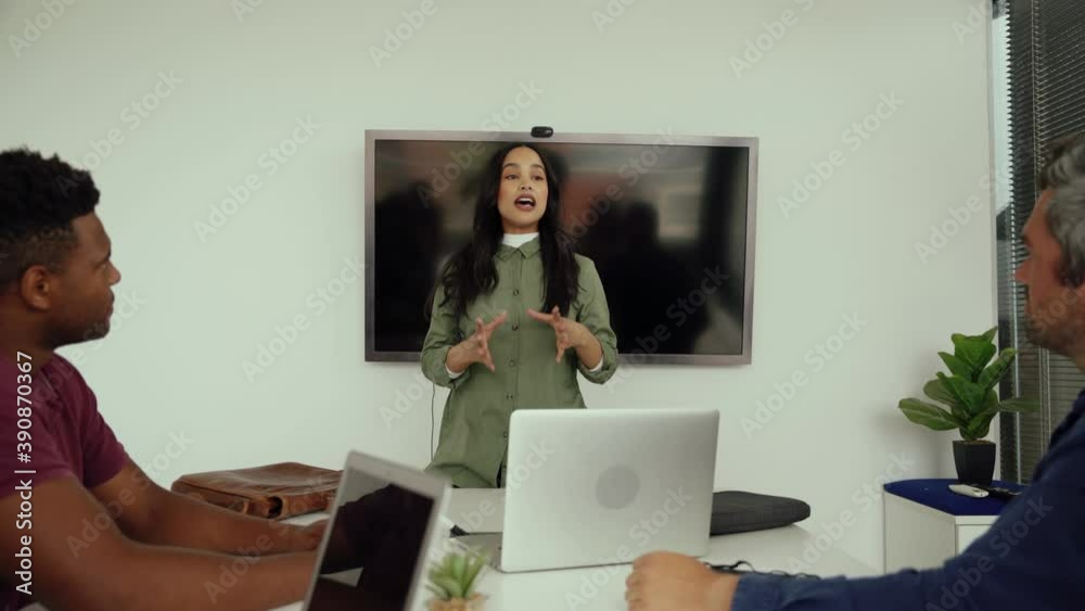 Confident mixed race empowered business woman presenting speech to colleagues gathered around table in board room 