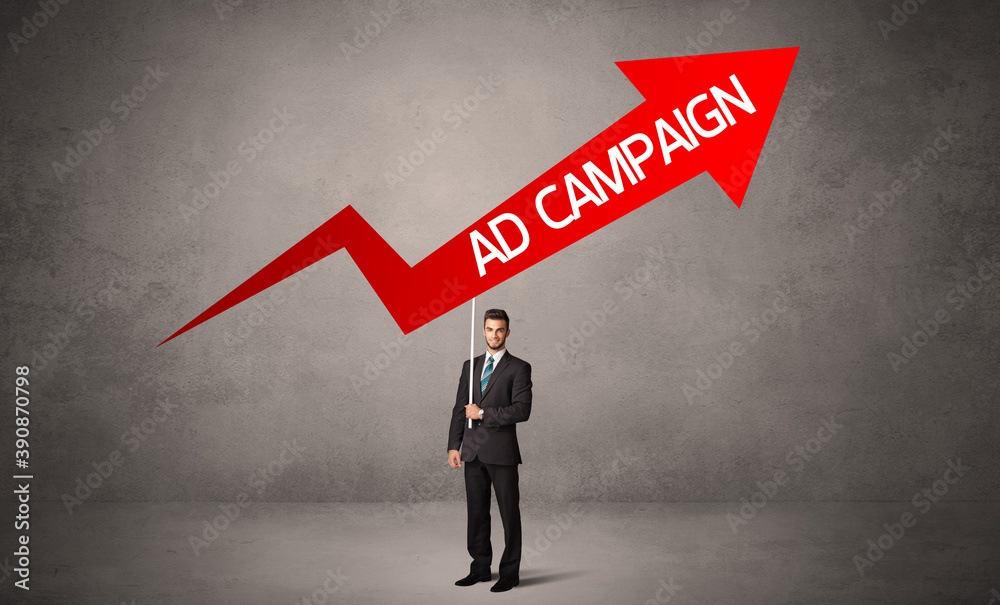 Obraz premium Young business person in casual holding road sign with AD CAMPAIGN inscription, business direction concept
