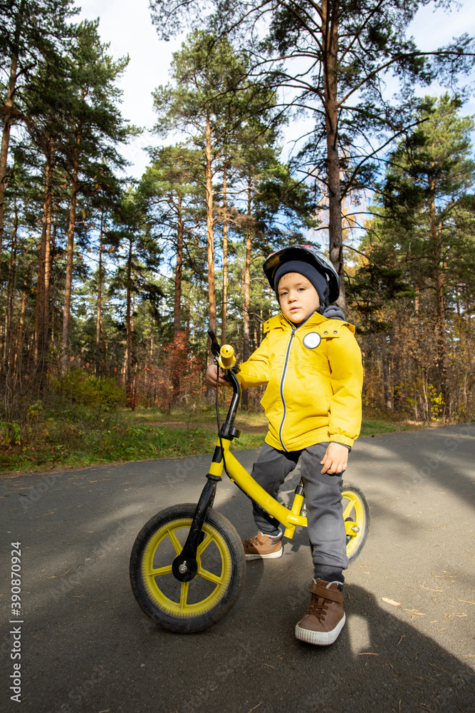 Adorable boy in casualwear and protective helmet standing by his balance bike Adorable boy in casualwear and protective helmet standing by his balance bike