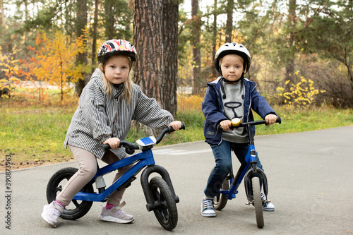 Two friendly little kids in casualwear and protective helmets sitting on bikes © pressmaster
