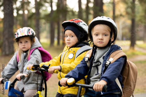 Group of little kids in protective helmets sitting on their balance bikes