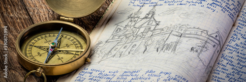 Vintage brass compass and old travel journal with handwriting and pencil sketches (property release attached), travel concept.