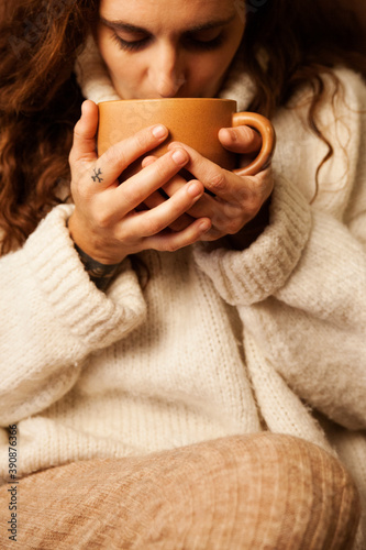 Girl resting on the sofa smelling a cup of coffee.