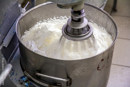 Huge bowl with white cream for cakes. Whisking process. Massive production .