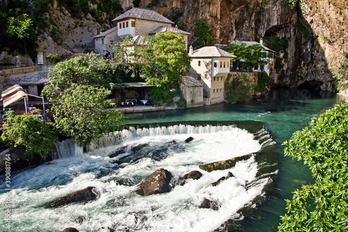 Fototapeta Naklejka Na Ścianę i Meble -  Dervish house on Buna spring with a small waterfall and a cave nearby in a sunny summer day in Blagaj, Bosnia and Herzegovina.