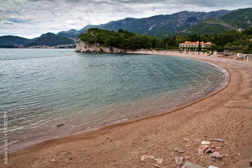 Sandy Queen's and King's beach of Adriatic sea and Villa Milocer and mountains covered with trees in the background in Montenegro. photo