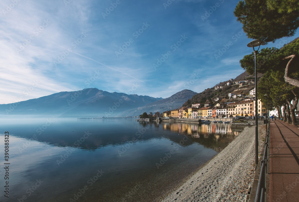 Calm water of the lake reflects the colorful houses of the romantic village on a clear winter day.Christmas holidays on Lake Como,Lombardy,Italian lakes,Italy