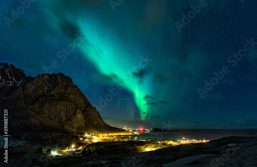 Aurora boreal sobre un pueblo de montaña en las islas Lofoten