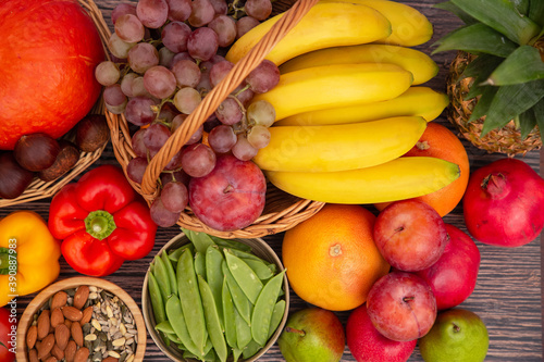 Group vegetables and Fruits Apples  grapes  oranges  and bananas in the wooden basket with carrots  tomatoes  guava  chili  eggplant  and salad on the table.Healthy food concept