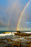 Early morning surf casting fishermen on the island of Oahu with a double rainbow and high surf