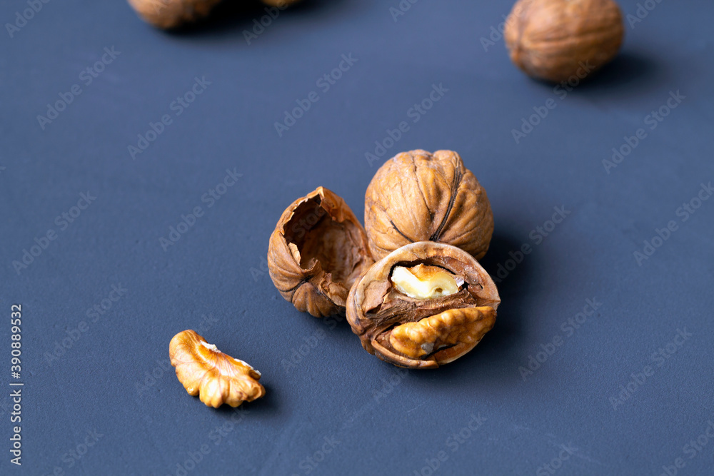 close-up peeled walnuts in shells on a black table and in a glass jar. brown nuts on a dark-blue background. copy space. dried walnut and fruit.  - obrazy, fototapety, plakaty 