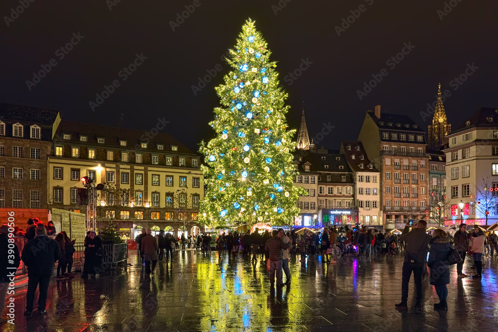 Strasbourg, France. The city's main Christmas tree on Place Kleber. It has traditionally imposing height, at least 30 meters. Tower of Strasbourg Cathedral is visible at the right border of the image.