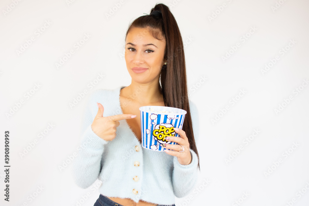 Young cute woman eating popcorn over white background. Looking at camera Young cute woman eating popcorn over white background. Looking at camera