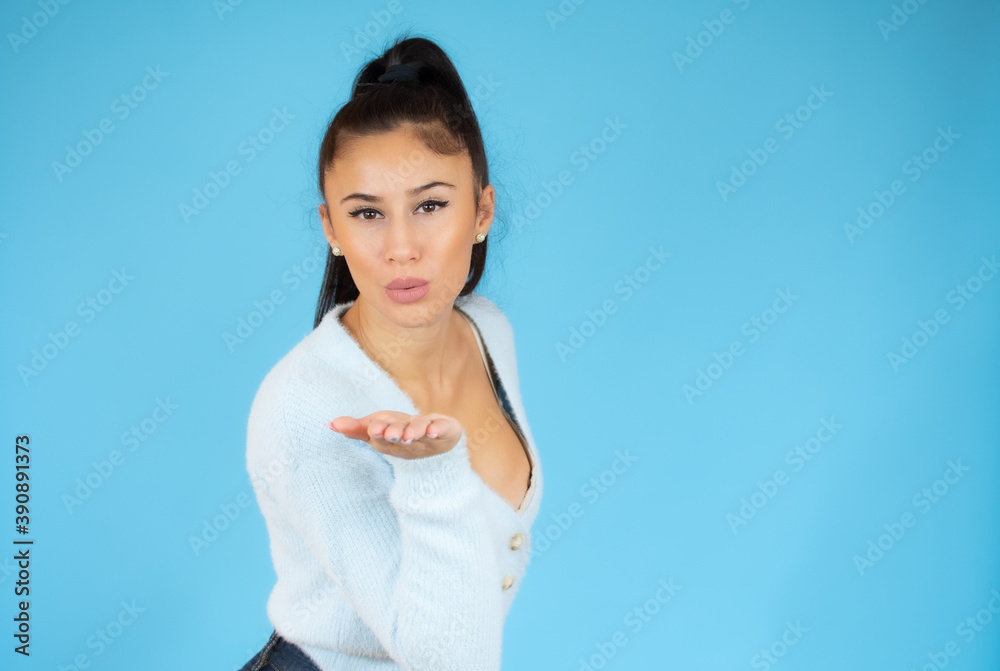 Pretty young woman sending kisses over blue background. Pretty young woman sending kisses over blue background.