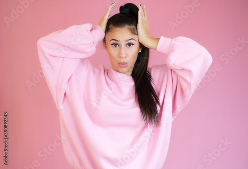 Surprised young woman in casual clothes over pink background. Looking at camera.