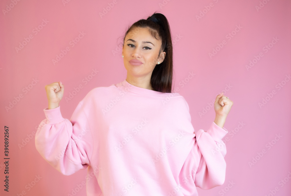 Photo of cheerful beautiful young woman standing isolated over pink wall background. Looking camera showing winner gesture. Photo of cheerful beautiful young woman standing isolated over pink wall background. Looking camera showing winner gesture.