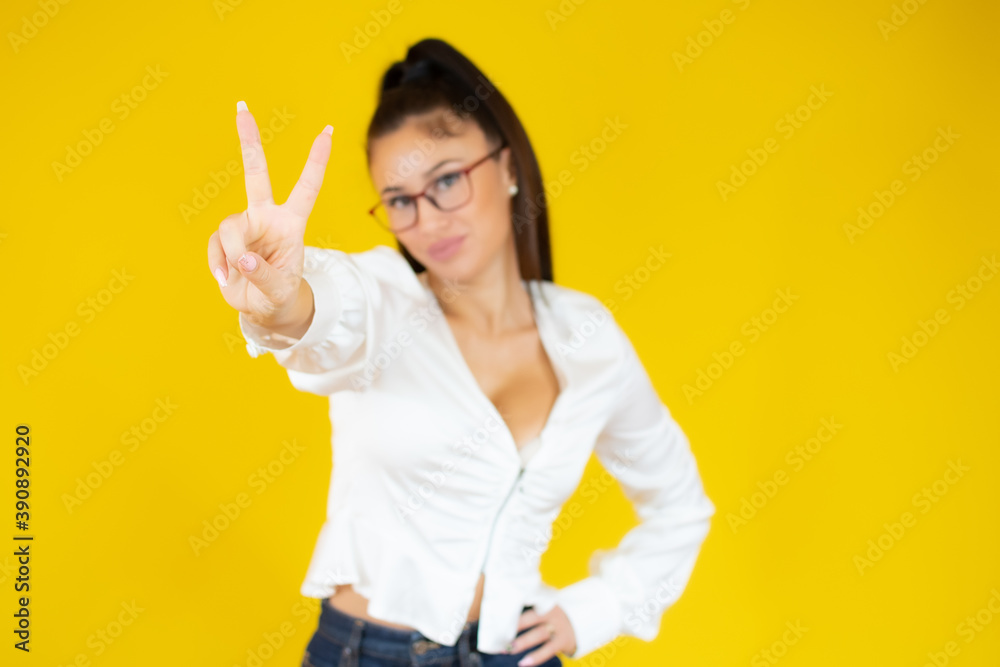 Portrait of a smiling businesswoman showing peace gesture isolated over yellow background Portrait of a smiling businesswoman showing peace gesture isolated over yellow background