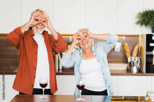 Cheerful elderly caucasian couple fooling around and having fun together at home in the kitchen