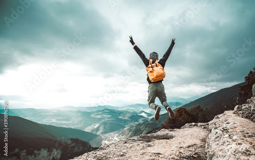 Hiker jumping on the top of the mountain - Successful man raising arms raising arms up.