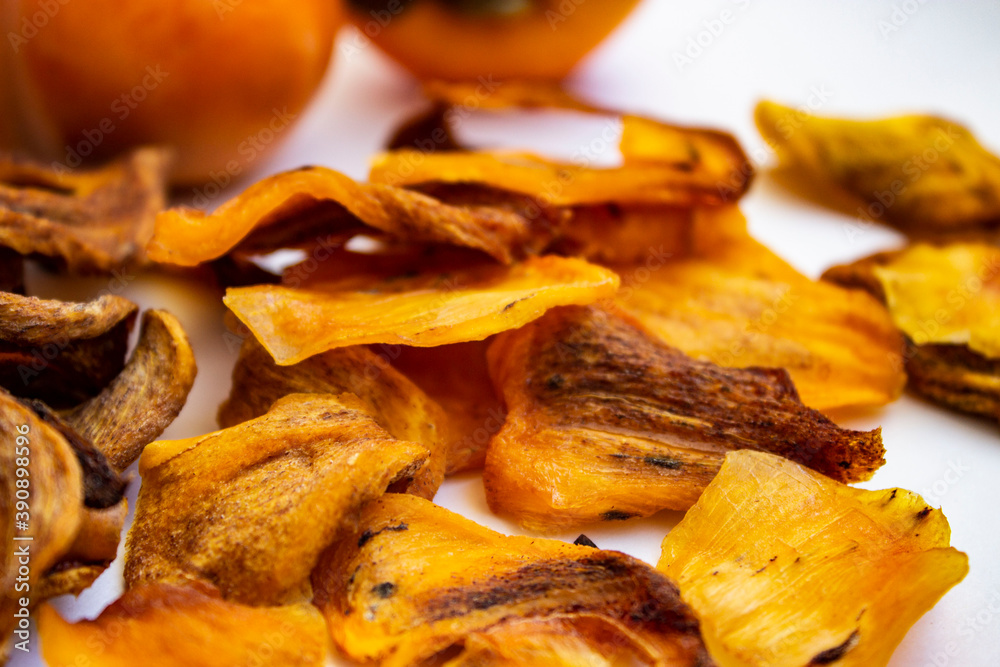 Chocolate persimmon, kinglet. Dried thin slices, fruit chips. Healthy food and snacks. Fruits are orange and brown in color. Light background. Chocolate persimmon, kinglet. Dried thin slices, fruit chips. Healthy food and snacks. Fruits are orange and brown in color. Light background.
