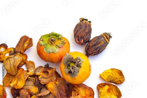 Chocolate persimmon, kinglet. Large dried fruit whole, brown-yellow with grooves. Thin slices, fruit chips. The ripe fruit is orange in color. Light background.