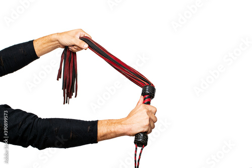Leather whip in male hand. Man's hand is holding black and red bdsm lash on isolated on white. Accessories for adult sexual games. Toys for BDSM, flogging, sexual fetish and spanking devices