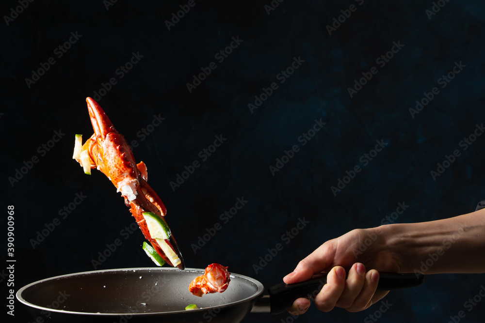 Φωτογραφία Close-up view of the chef toss up king crab legs with pieces of lime in a frying pan on dark blue background