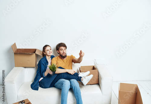 young couple sitting on white couch boxes moving lifestyle