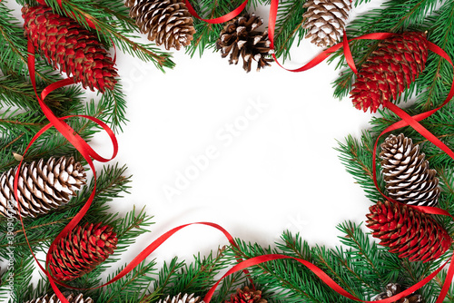 Christmas frame made of fir branches and cones on a white background with ribbons.