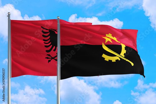 Angola and Albania national flag waving in the windy deep blue sky. Diplomacy and international relations concept.