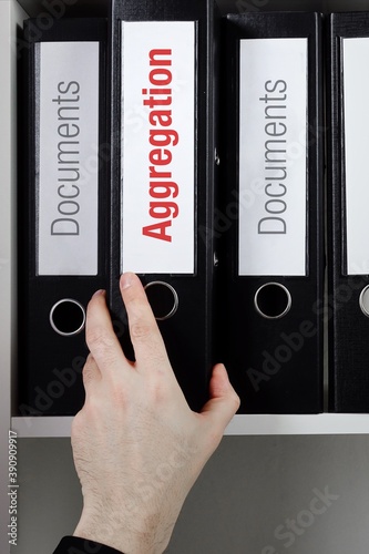Aggregation. File Folder is taking by a hand from office shelf. Red Text is on the label of the documents.