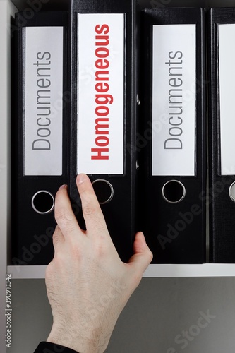 Homogeneous. File Folder is taking by a hand from office shelf. Red Text is on the label of the documents. photo