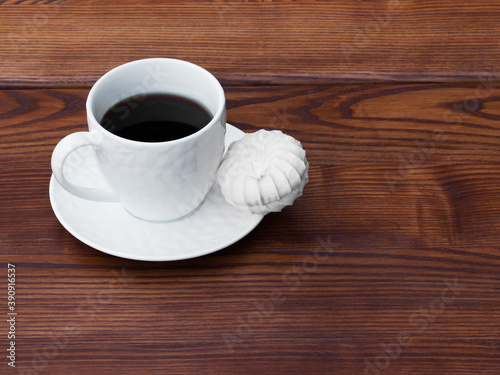 White cup of coffee and pink zefir on the wooden background. Traditional russian sweets like marshmallow. Copy space.