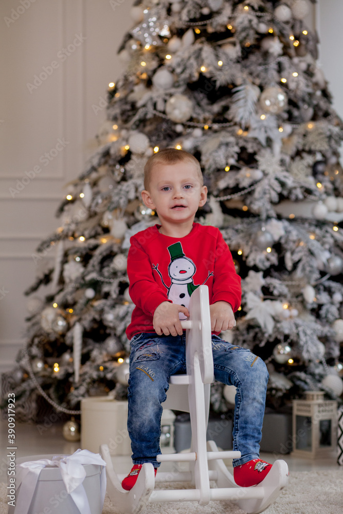 Little boy riding a cardboard horse near the Christmas tree Little boy riding a cardboard horse near the Christmas tree